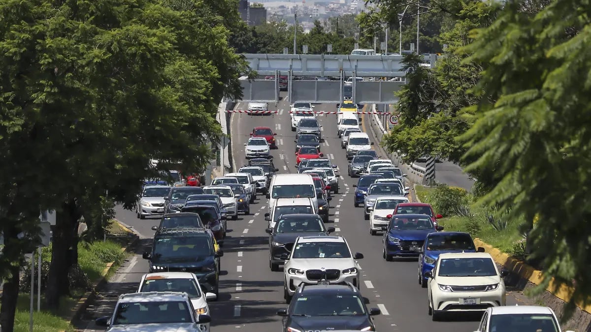 Aerial view of heavy traffic congestion on a multi-lane highway with cars and trucks lined up under trees