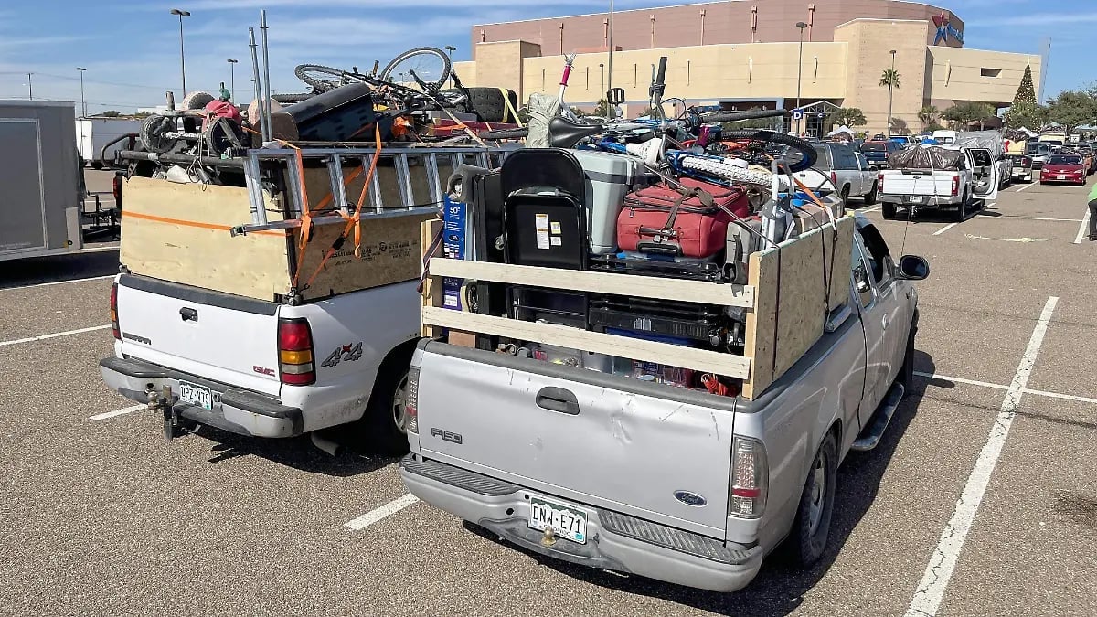 Pickup trucks loaded with tools, equipment, and construction materials parked in a large outdoor lot