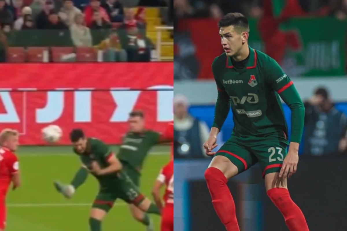 Footballer in dark green and red striped jersey with number 23 during a professional match, with stadium crowd in background