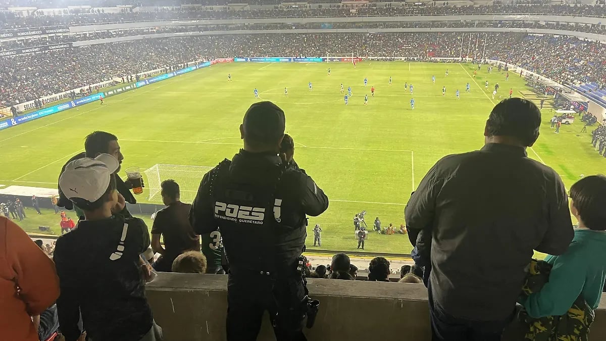 Spectators watching a soccer match from the stadium stands, viewing the pitch and players below