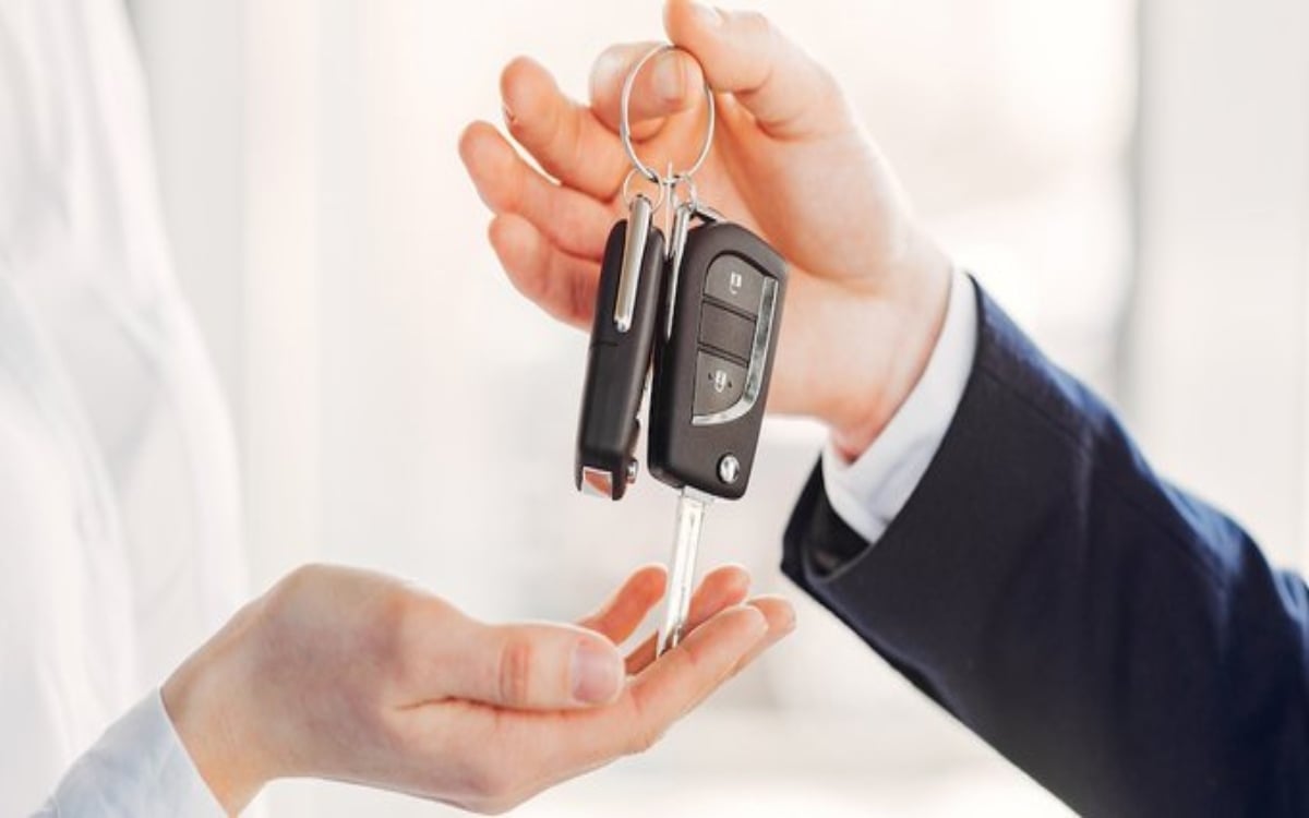 Person in business attire handing over car keys on a keychain to another person
